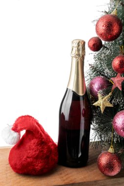 Beyaz arka planda Noel Baba şapkası ve Noel ağacı olan şampanya şişesi.