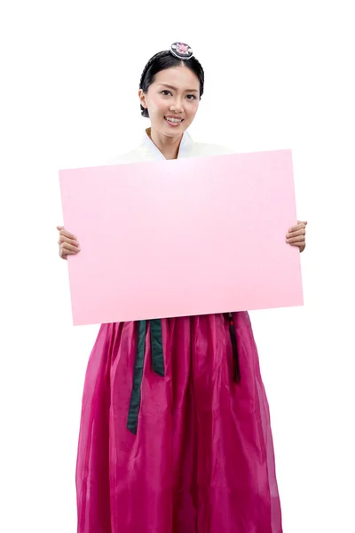 白い背景に隔離されたコピースペースのための空の紙を保持しながら 伝統的な韓国の民族衣装 韓服を着てアジアの女性 立って — ストック写真