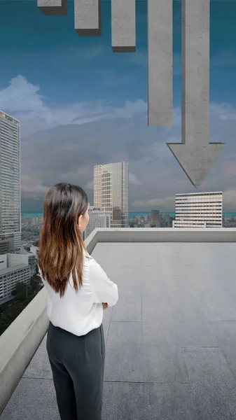 Asian businesswomen looking at decreased graph arrow with a cityscape background