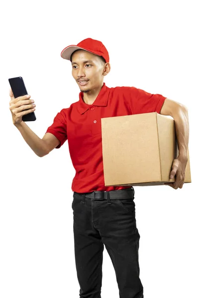 Repartidor Paquetes Con Sombrero Sosteniendo Teléfono Móvil Mientras Lleva Paquete — Foto de Stock