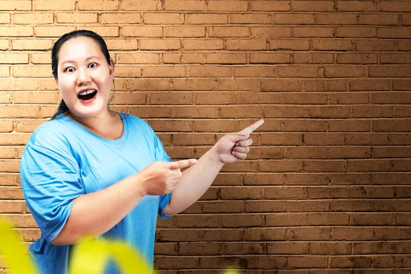 Asijské Tuk Nadváha Žena Vzrušeným Výrazem Ukazuje Něco Cihlovou Zdí — Stock fotografie