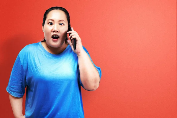 アジアの太った太りすぎ女性保持携帯電話で色の背景 — ストック写真