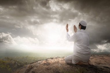 Müslüman bir adamın el kaldırarak, tepenin üstünde dua edişinin arkası.