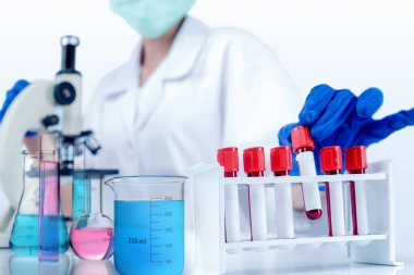 Dişi bilim adamları laboratuvar vitrinlerinde mikroskop ve renkli kimyasallarla test tüpleri alırlar. Ulusal Bilim Günü