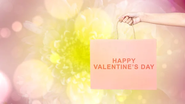 Human hand holding shopping bags with a colored background. Valentines day