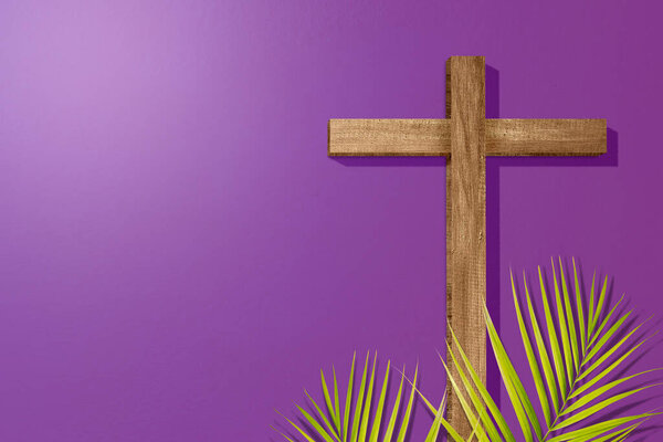 Cross and palm leaf on a colored background. Palm Sunday Concept