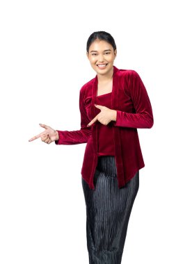 Asian girl wearing red kebaya traditional clothes pointing at something isolated over white background