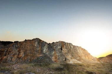 Rock hill and grass field with sunset sky background