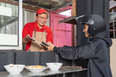 Asian man with a hat and apron receiving online order in the shop 