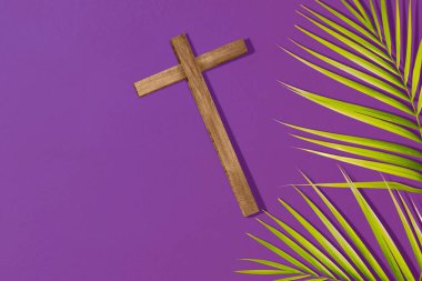 Cross and palm leaf on a colored background. Palm Sunday Concept
