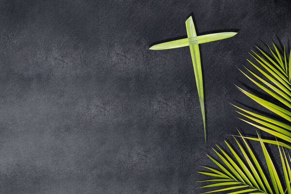Palm leaf with a cross shape on a black background. Palm Sunday Concept