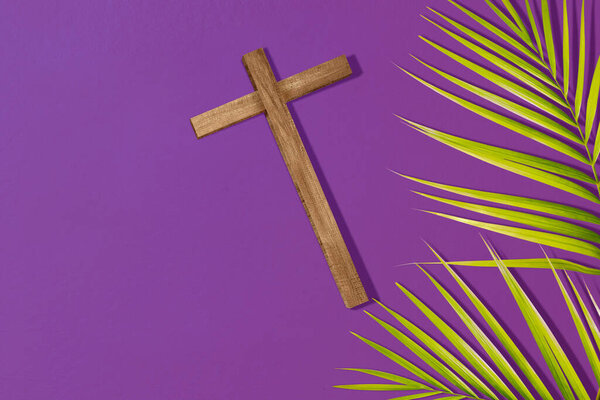 Cross and palm leaf on a colored background. Palm Sunday Concept