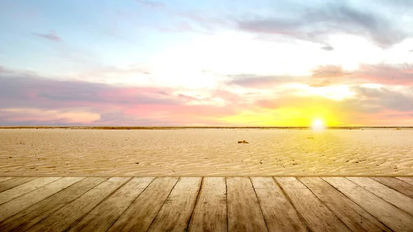 Wooden floor with views of sand dunes with a sunset sky background