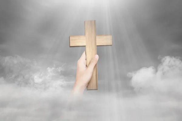 光を背景にキリスト教の十字架を持つ人間の手 — ストック写真