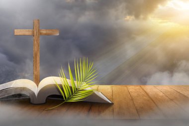 Çapraz ve günbatımı sahne arkaplanlı açık kitap ve palmiye yaprağı. Palm Sunday Konsepti