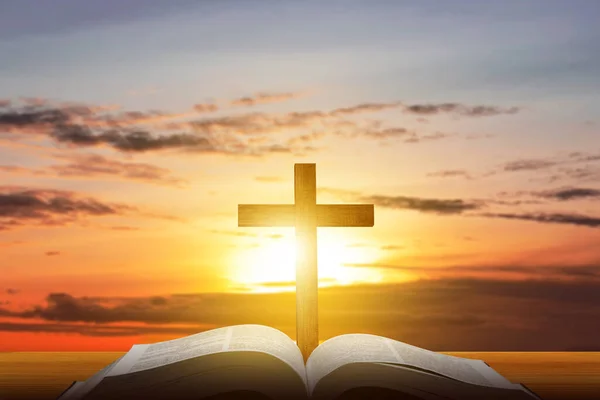 Christian Cross and open book with a sunset scene background
