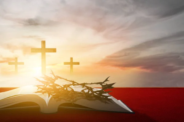 Christian Cross and open book with a crown of thorns with a sunset scene background