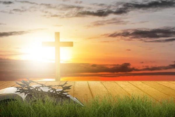 Christian Cross and open book with a crown of thorns with a sunset scene background