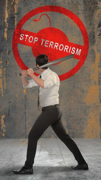 一名商人手持棒球棒并在墙上贴有制止恐怖主义的标志的后视镜 — 图库照片