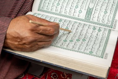 Müslüman bir adam beyaz arka planda izole bir şekilde Kuran okuyup namaz kılıyor.