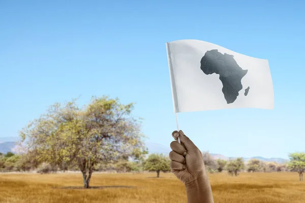 A human hand holding a Flag with African maps with a blue sky background. Africa day concept
