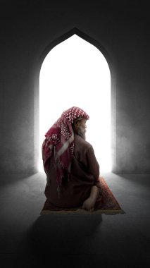 Sakallı ve sakallı müslüman bir adam caminin içindeki halıda namaz kılıyor.
