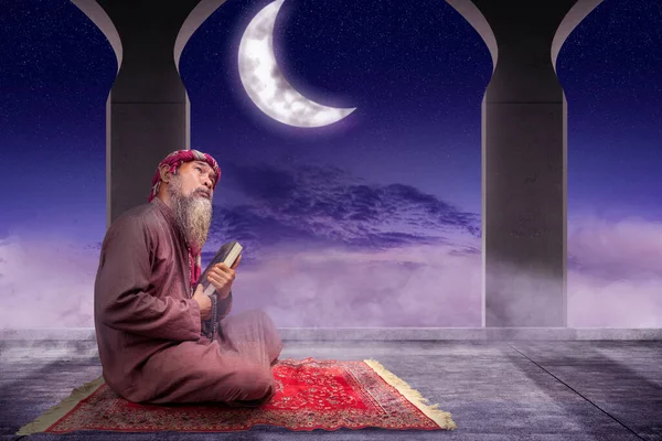 穆斯林男子 留着胡子 头戴头巾 手里拿着 古兰经 手里拿着祈祷珠子 带着夜景背景 — 图库照片