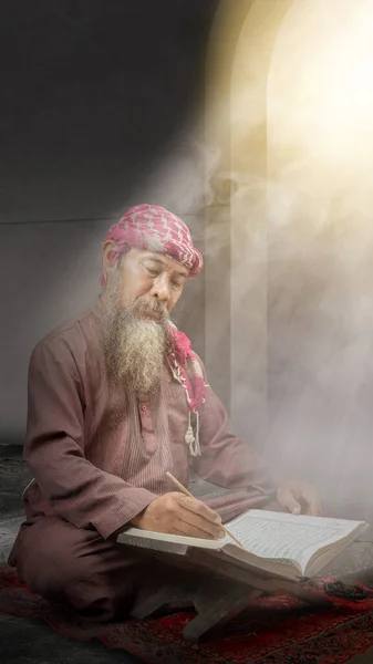 穆斯林男子 留着胡子 头戴头巾 坐着诵读 古兰经 躺在清真寺里的祈祷地毯上 — 图库照片