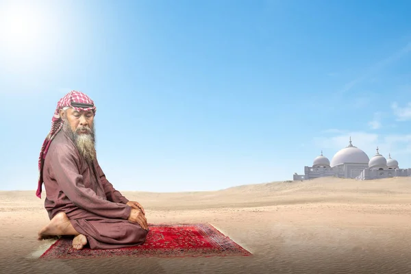 青い空の背景を持つ祈りの敷物の上で祈りの位置 サラト でAgalとKefiyehを身に着けている髭を持つイスラム教徒の男 — ストック写真