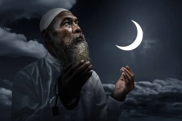 穆斯林男子 留着胡须 头戴白帽 手上拿着祈祷珠子 背景是夜景 — 图库照片