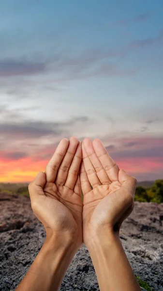 Muslim man raised hands and prayed with sunset sky background