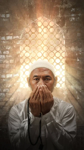モスクの中で手に祈りのビーズで祈る白い帽子をかぶって髭を生やしたイスラム教徒の男 — ストック写真
