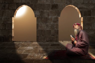 Sakallı Müslüman bir adam, camiinin içinde Kuran ve tespih taşıyan bir keffiyeh giyiyor.