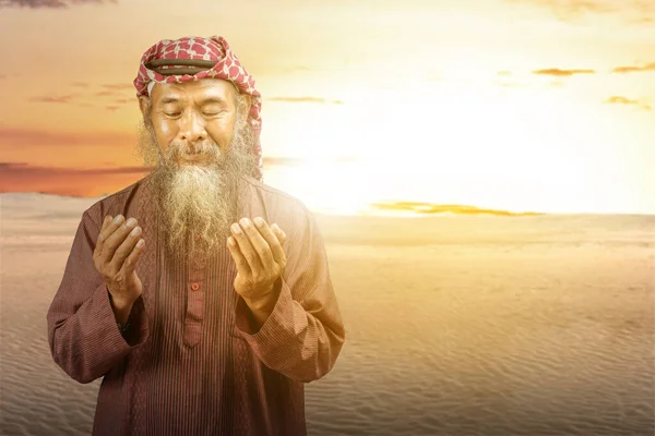 日没シーンを背景に手を上げながら祈りの中でAgalとKefiyehを身に着けている髭を持つイスラム教徒の男 — ストック写真