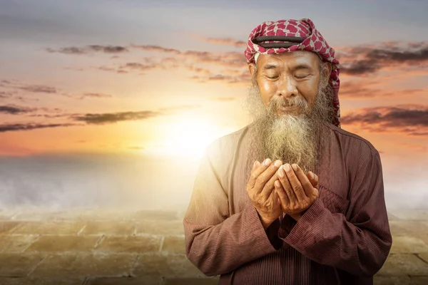 穆斯林男子 留着胡子 头戴头巾 头戴头巾 双手举着夕阳西下的背景 进行祈祷 — 图库照片