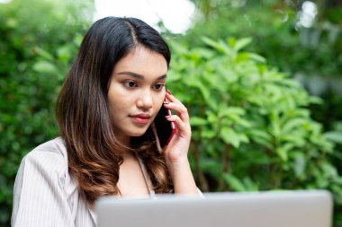 Kafede dizüstü bilgisayarlı cep telefonu kullanan Asyalı bir iş kadını.