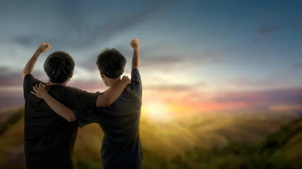 Rear view of two men standing with sunset scene background. International Day of Friendship Concept