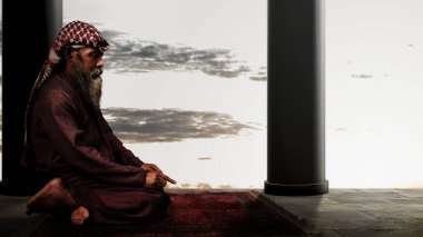 Sakallı ve sakallı müslüman bir adam caminin içindeki halıda namaz kılıyor.