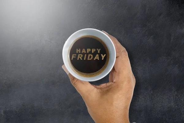A human hand holding a coffee cup with a Happy Friday text. Happy Friday concept