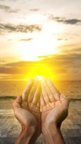 Muslim man raised hands and prayed with the sunset scene background