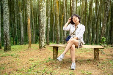 Ormandaki bankta oturan Asyalı kadın. Seyahat etkinliği