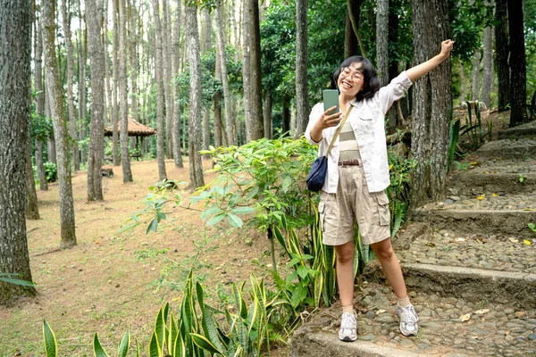 Ormanda Mutlu Bir Ifadeyle Cep Telefonu Kullanan Asyalı Bir Kadın — Stok fotoğraf