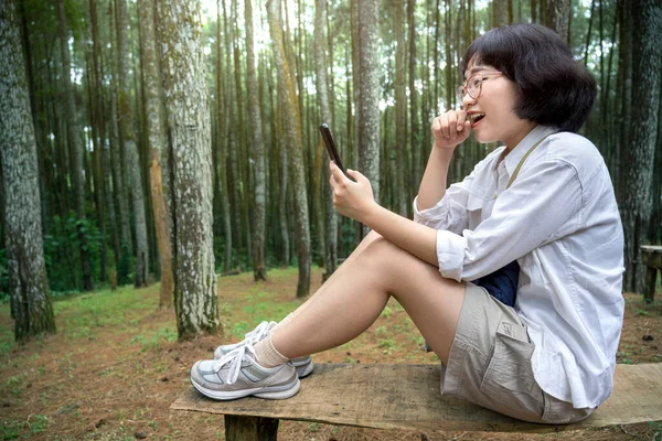 Azjatka Siedząca Ławce Używająca Telefonu Komórkowego Lesie Działalność Podróżnicza — Zdjęcie stockowe
