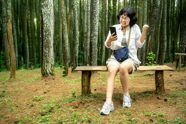 Mujer Asiática Sentada Banco Usando Teléfono Móvil Con Una Expresión —  Fotos de Stock