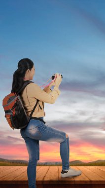 Asian woman with a backpack holding the camera. World Photography Day