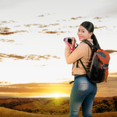 Asian woman with a backpack holding the camera. World Photography Day