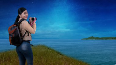 Asian woman with a backpack holding the camera. World Photography Day