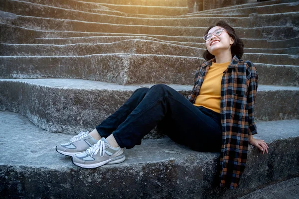 日光の背景を持つ石のステップに座っているアジアの女性 — ストック写真