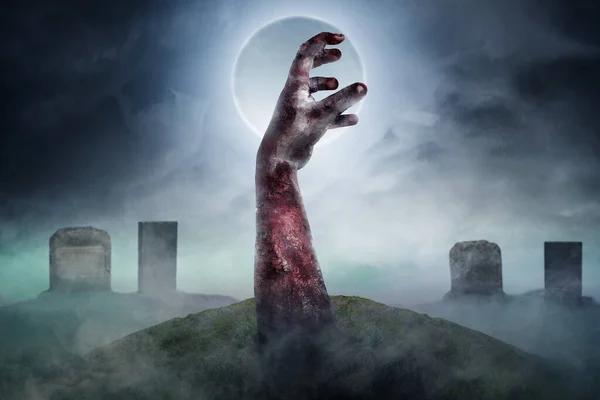 Zombie\'s hand with wounds rises up on the graveyard with full moon background. Scary Halloween concept