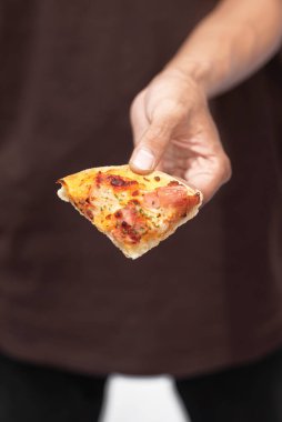 Beyaz arka planı olan bir dilim pizzayı tutan bir insan eli.